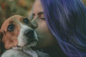 woman kissing brown and white dog